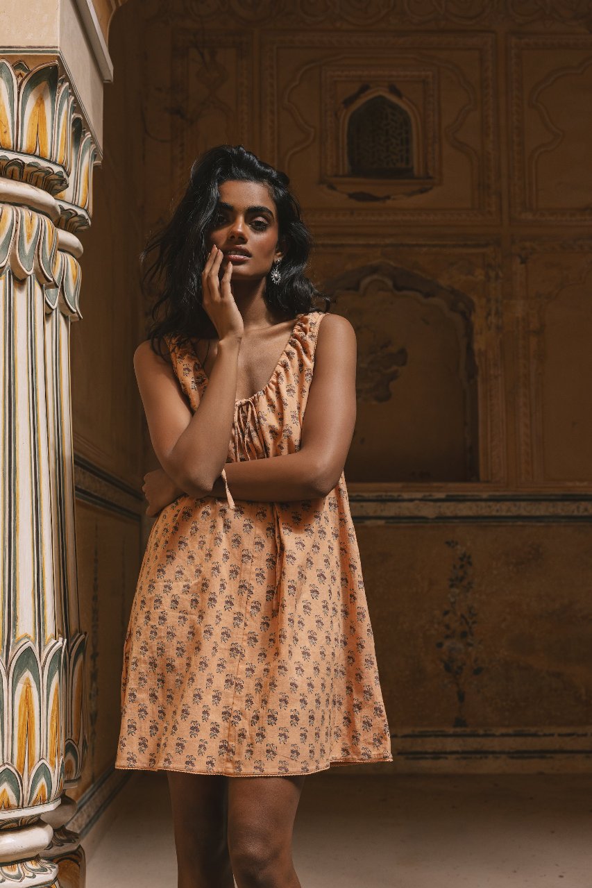 Sundress Mini Peach — studio full length front view, model facing camera, sleeveless mini sundress with tie-gather neckline, short hemline, hand block print peach floral cotton, artisan Jaipur India | Daughters of India