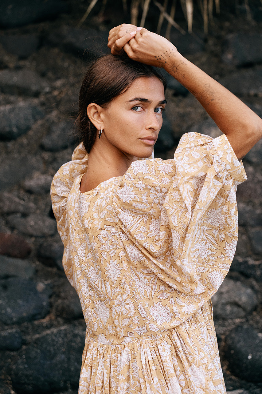 Daughters of India Kyra Midi Dress in Cumin — back close-up by volcanic rocks, billowed sleeves, cumin floral print